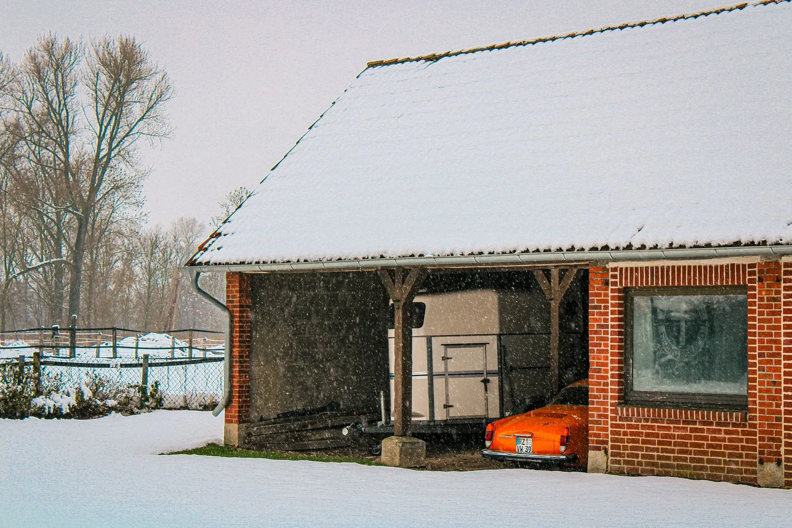 Voiture ancienne bâchée dans un garage sec, batterie déconnectée et pneus sur cales, ambiance hivernale